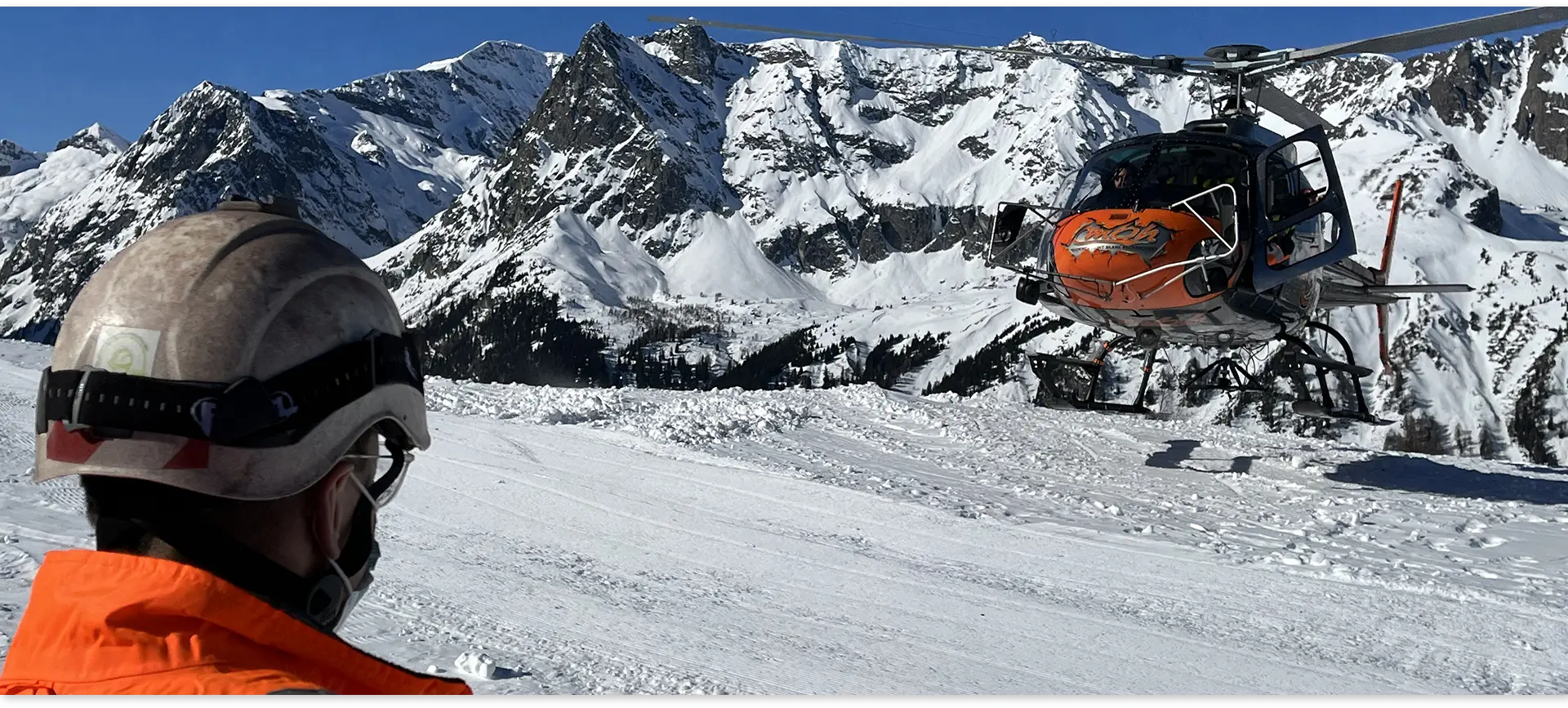 photo d'un ouvrier en montagne face à un hélicoptère