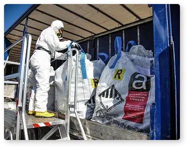 photo d'un ouvrier en combinaison manipulant des sacs d'amiante