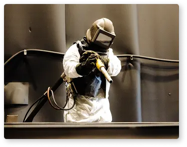photo d'un ouvrier en combinaison en train de préparer une surface metallique pour le revêtement